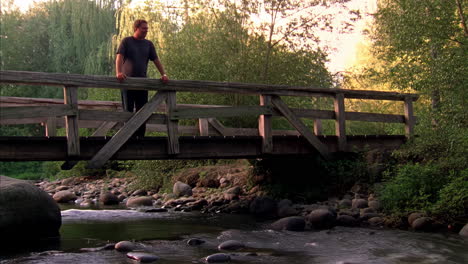 hombre en un puente de madera sobre un río