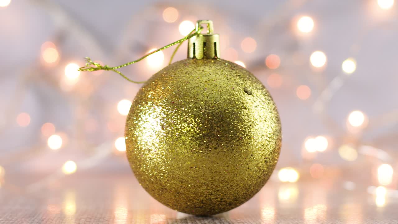 ornamento navideño de brillo dorado con luces parpadeantes detrás