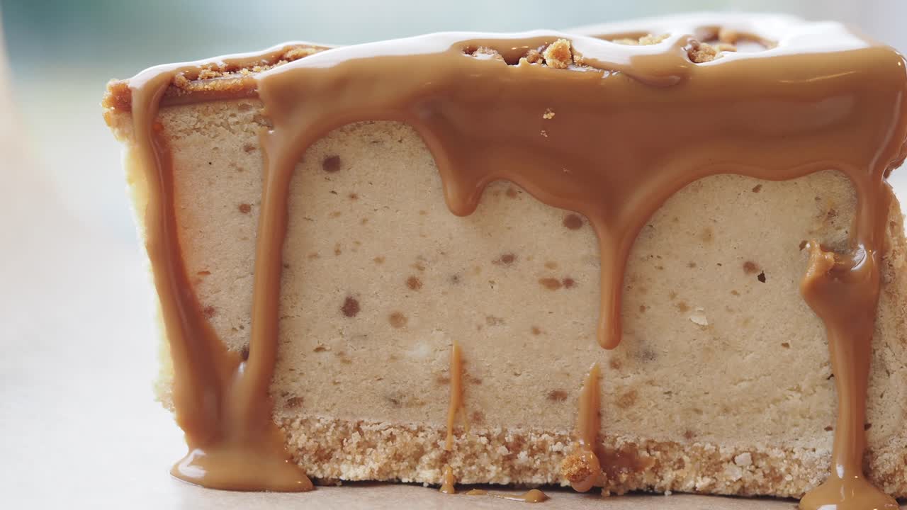 Fetta di cheesecake con salsa al caramello che cola.
