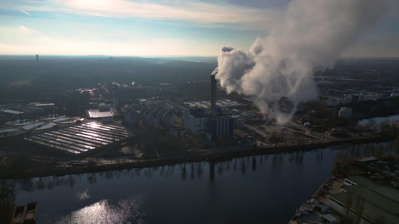 Industrial chimneys emitting white smoke over city skyline under blue sky, concept of pollution. Unbelievable aerial view flight panorama overview drone