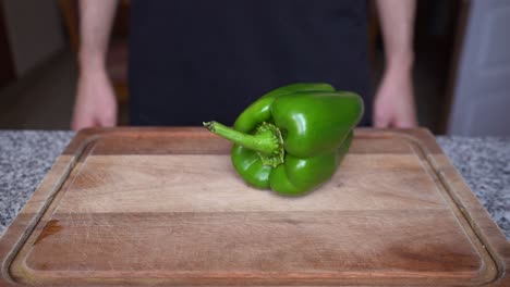 primer plano de pimiento verde rodando sobre una tabla de madera