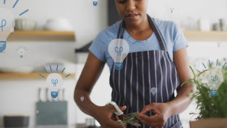 Animation-of-lightbulbs-over-afrcian-american-woman-preparing-food-in-kitchen