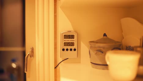 digital thermometer mounted on interior wall of a house with warm lighting