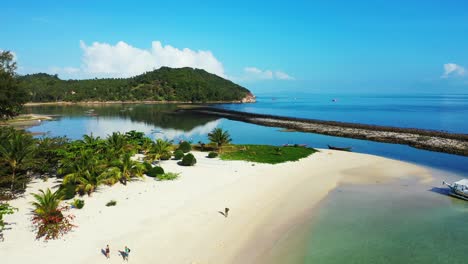 peaceful seascape with blue sea and calm shallow lagoon washing beautiful tropical garden of resort with palm trees on white beach, thailand