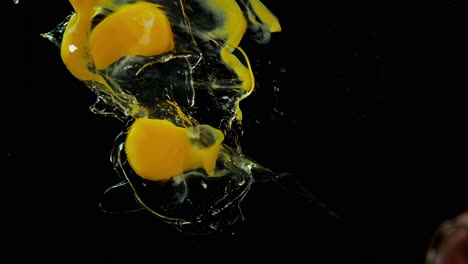 raw eggs splash into water against black background