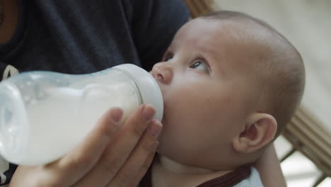 close up on a baby boy during feeding from a bottle with baby nutrition