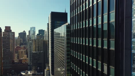 Ascending-footage-along-glossy-wall-of-high-rise-building.-Revealing-cityscape-with-skyscrapers.-Manhattan,-New-York-City,-USA