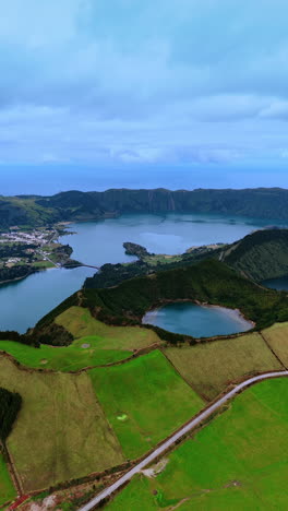 urban area on the waterfront of the lake located in the crater of sleeping volcano. picturesque scenery of the nature at the azorean islands. vertical video.