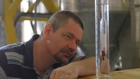 male worker examining gin in measuring cylinder 4k