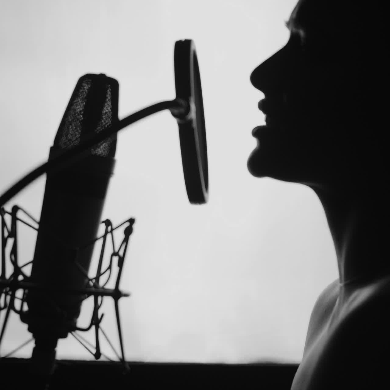Woman singing in the recording studio. Profile of a woman with a beautiful face and lips. Black and White