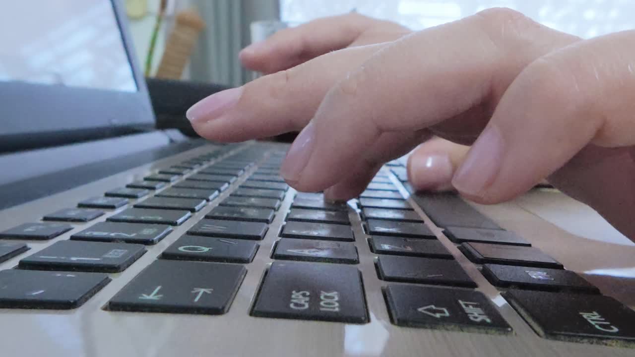 Side perspective of professional woman's hands diligently typing on a laptop, focused on a business