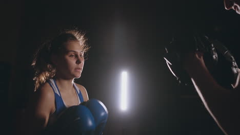 woman punches the focus mitts in the boxing gym