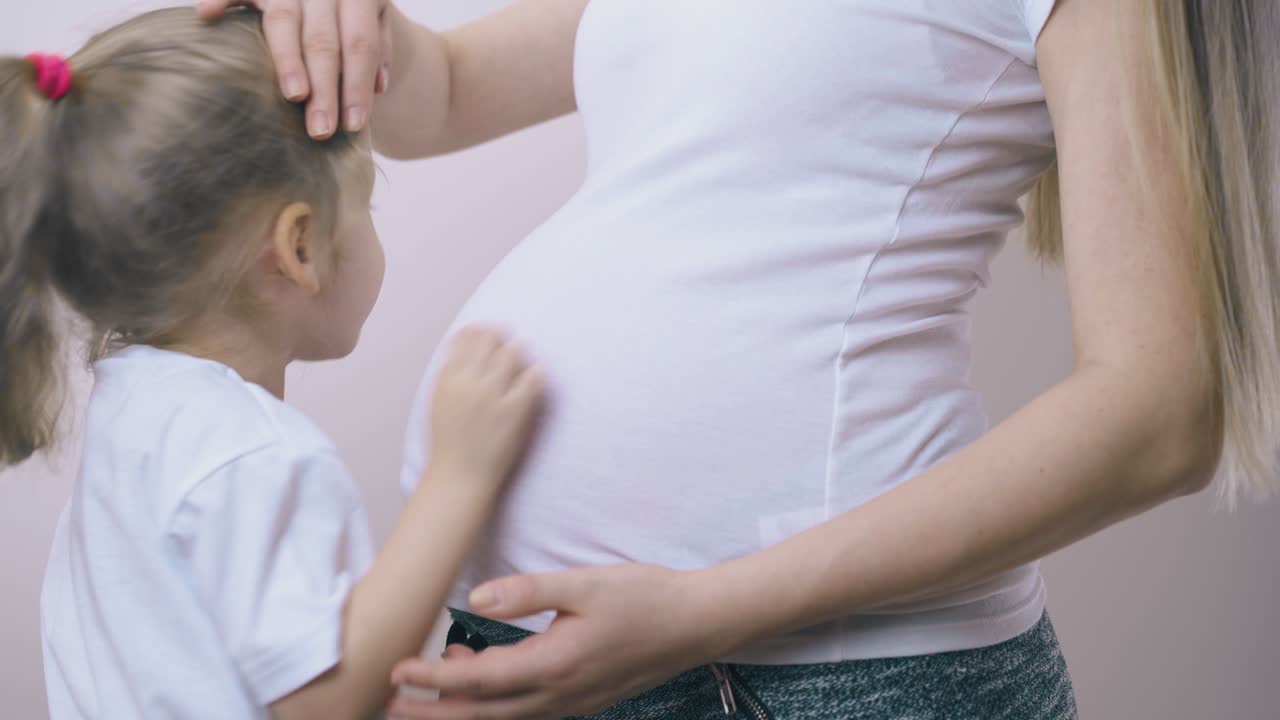 임신 한 어머니 가 딸 을  ⁇ 안고 배 에 아기 를 안고 있다