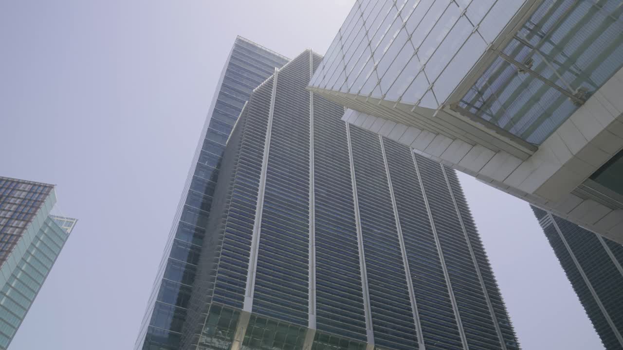 Movimiento de cámara cinematográfico con inclinación que revela la altura y el diseño de las torres ADGM en Abu Dabi, filmado a la luz del día con una cámara mirrorless.