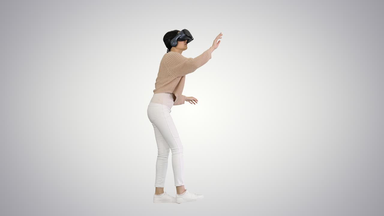 una joven linda caminando y usando auriculares vr interactivos en el fondo del gradiente