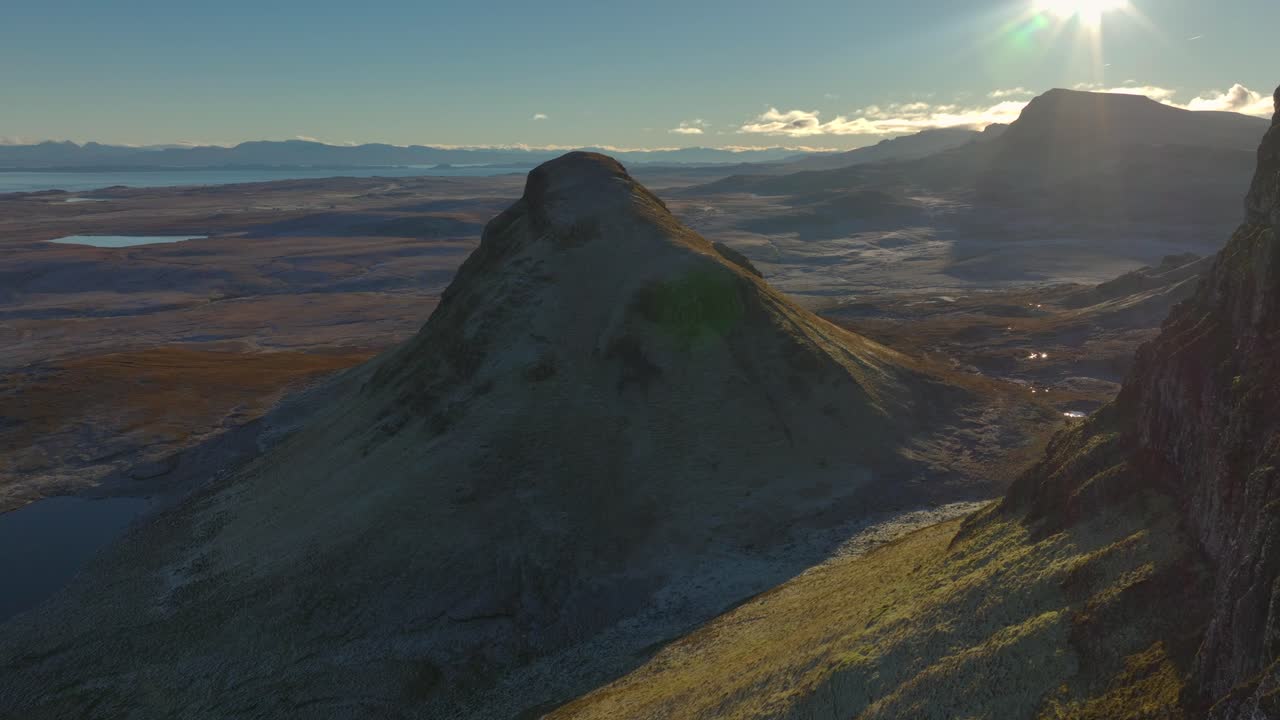 volando cerca más allá del borde del acantilado desmoronado hacia el pico de deslizamiento de tierra aislado con la estrella del sol revela