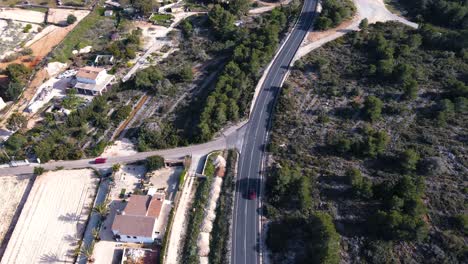 fotografía aérea de un coche conduciendo a lo largo de una carretera en calpe, españa, serpenteando a través de un paisaje pintoresco con montañas en una autopista vacía