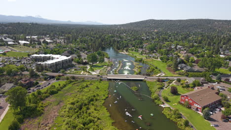 drone flight over deschutes river in bend. people tubing and surfing on the river.drone ascending shot.
