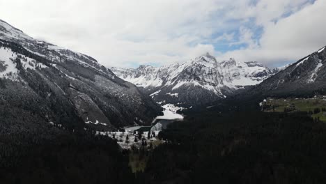 A-majestic-aerial-view-of-the-Swiss-Alps,-showcasing-peaks-adorned-with-snow-and-veiled-by-clouds-and-mist,-located-close-to-Glarus,-Switzerland