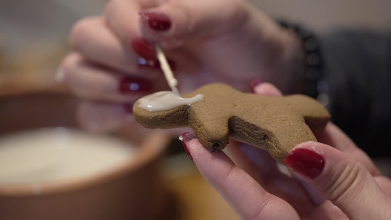 Close-up shot of a lady putting icing on a gingerbread man