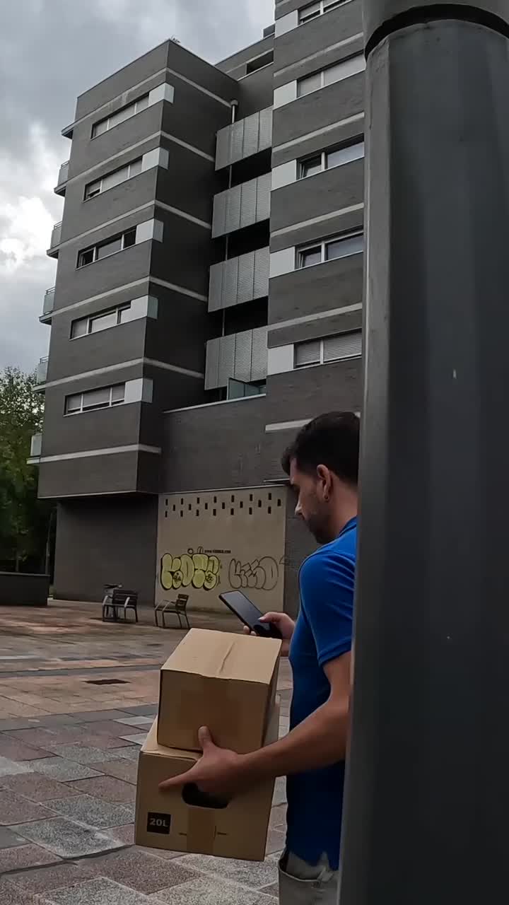 Man with box and phone near building