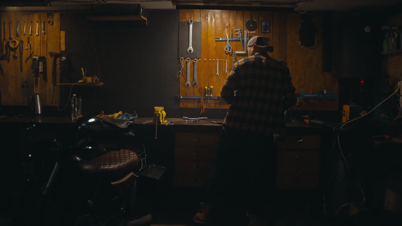 Rear view of a confident mechanic working on a workbench among many tools in his workshop