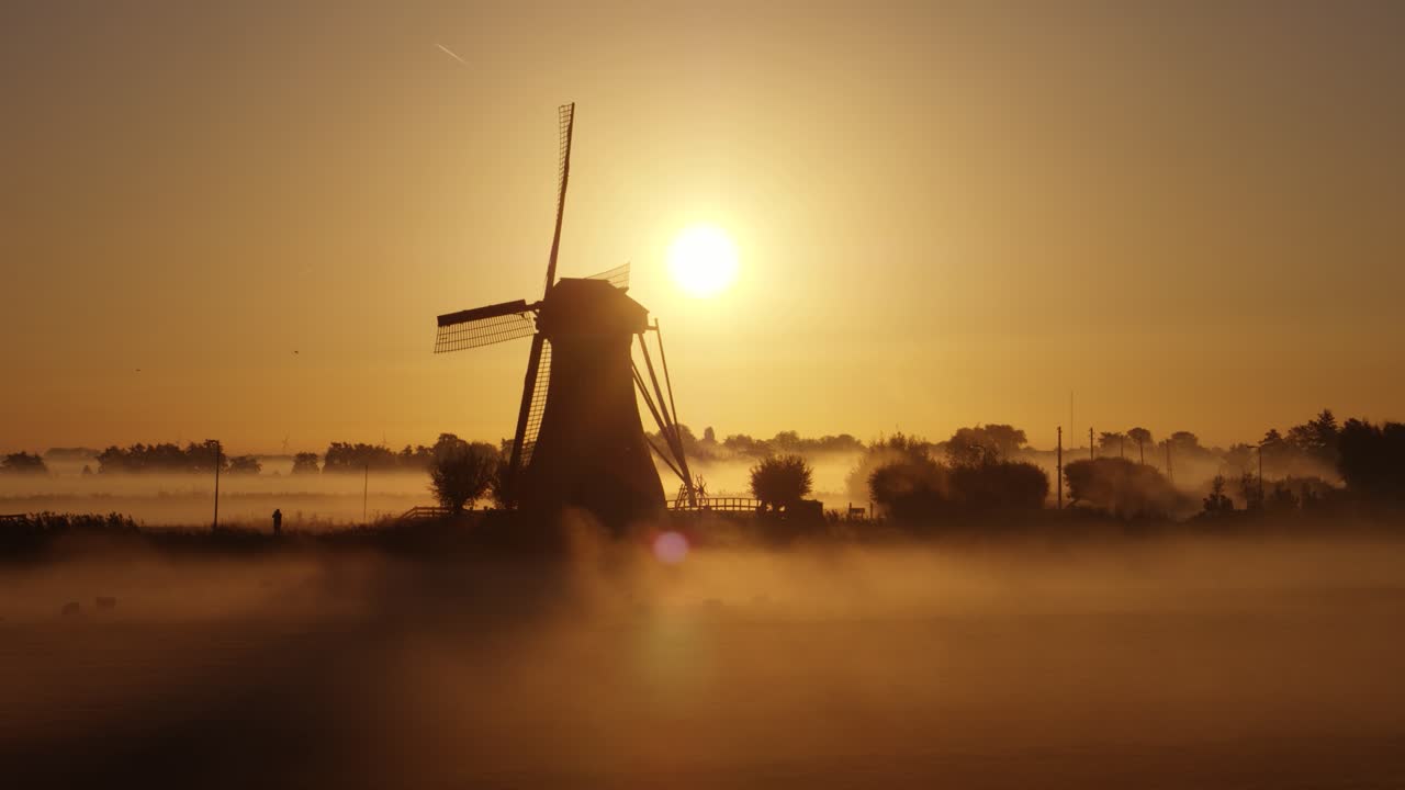 안개 속 에 있는 네덜란드 의 풍차 위 에서 해가 뜨는 것