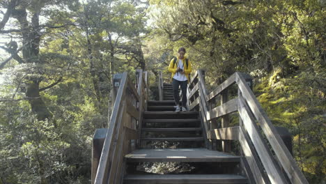 girl in yellow jacket walking down hiking down hill carrying camera