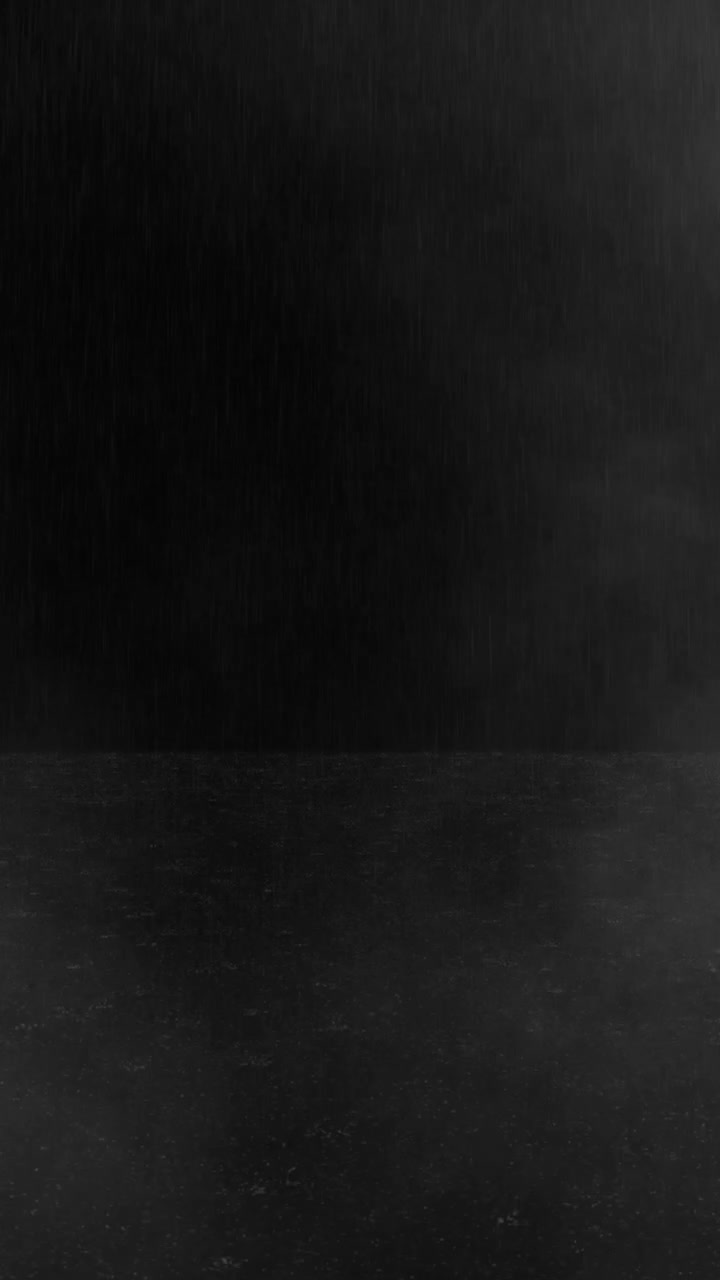 Vertical video of rain falling and splashing on a dark floor surface.