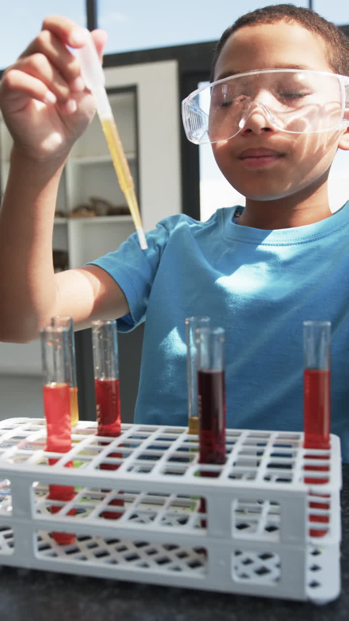 Vertical video: In school, child conducting science experiment with test tubes and pipette
