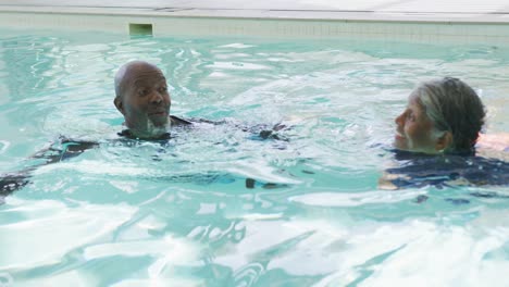 video of happy senior african american couple swimming in pool