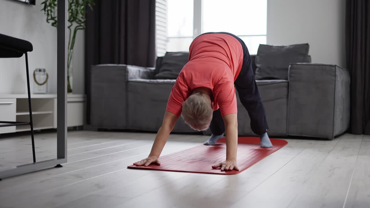 anciana ejercitando las piernas acostada en un tapete de yoga en la sala de estar