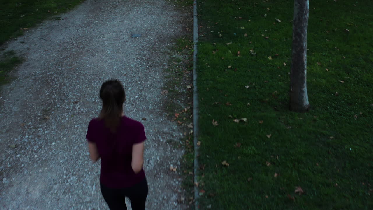 Aerial down shot of a woman jogging through Enrique Tierno Galván Park