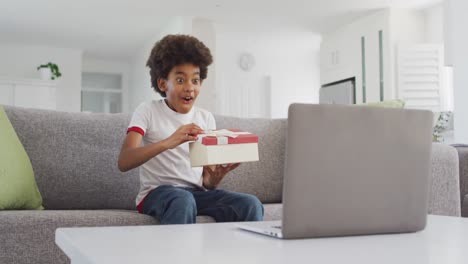 Kleiner-Junge-öffnet-Geschenkbox,-Während-Er-Auf-Seinem-Laptop-Einen-Videochat-Führt