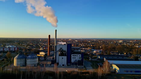 steam from a district heating station smokestack in a european town - aerial orbit