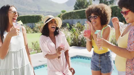 felices amigas diversas haciendo brindis y sonriendo en la fiesta de la piscina