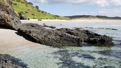 tiro inclinado hacia abajo de la playa de arena tropical con arrecifes de coral bajo aguas transparentes en verano - bahía de los espíritus, nueva zelanda