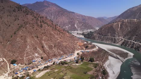 Aerial-View-of-River-Valley-and-Settlements:-Scenic-Beauty-and-Human-Interaction,-Winding-River-Mountainous-Landscape,-Lush-green-patches-of-Cultivated-Land,-with-Rocky-Terrain