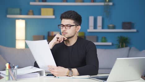 un joven pensativo trabajando en el papeleo.