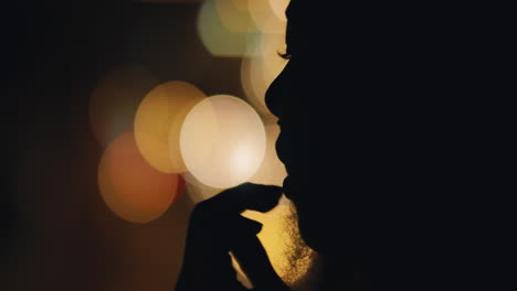 beautiful silhouette of woman blowing kiss with bokeh lights in background