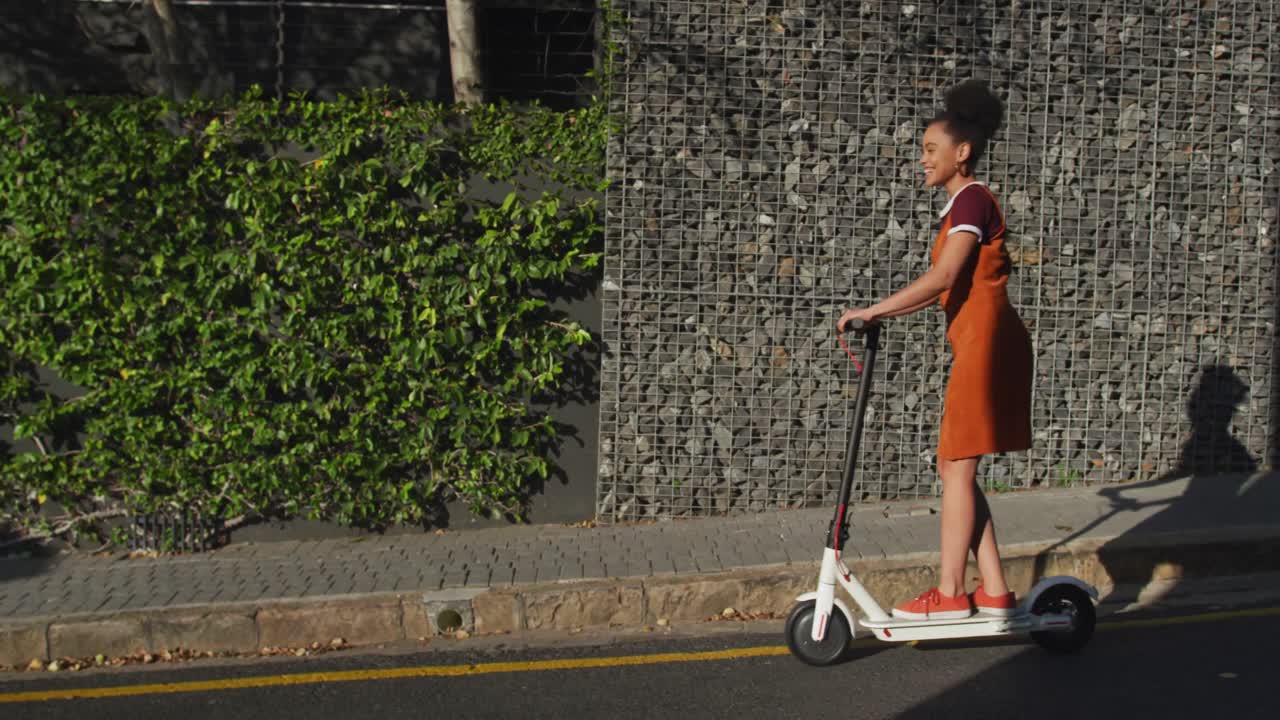 Mixed race woman riding electric scooter on street
