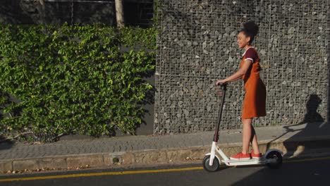 mixed race woman riding electric scooter on street