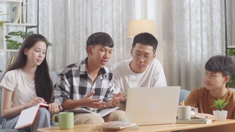 asian teen group studying on a laptop at home. taking online course, a boy in plaid shirt explaining, making presentation, writing into notebook