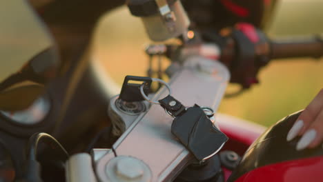 un primer plano de la mano de una persona quitando delicadamente una llave de la ignición de una motocicleta