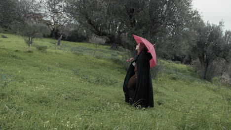 enigmatic woman with red umbrella looks around in a gloomy countryside