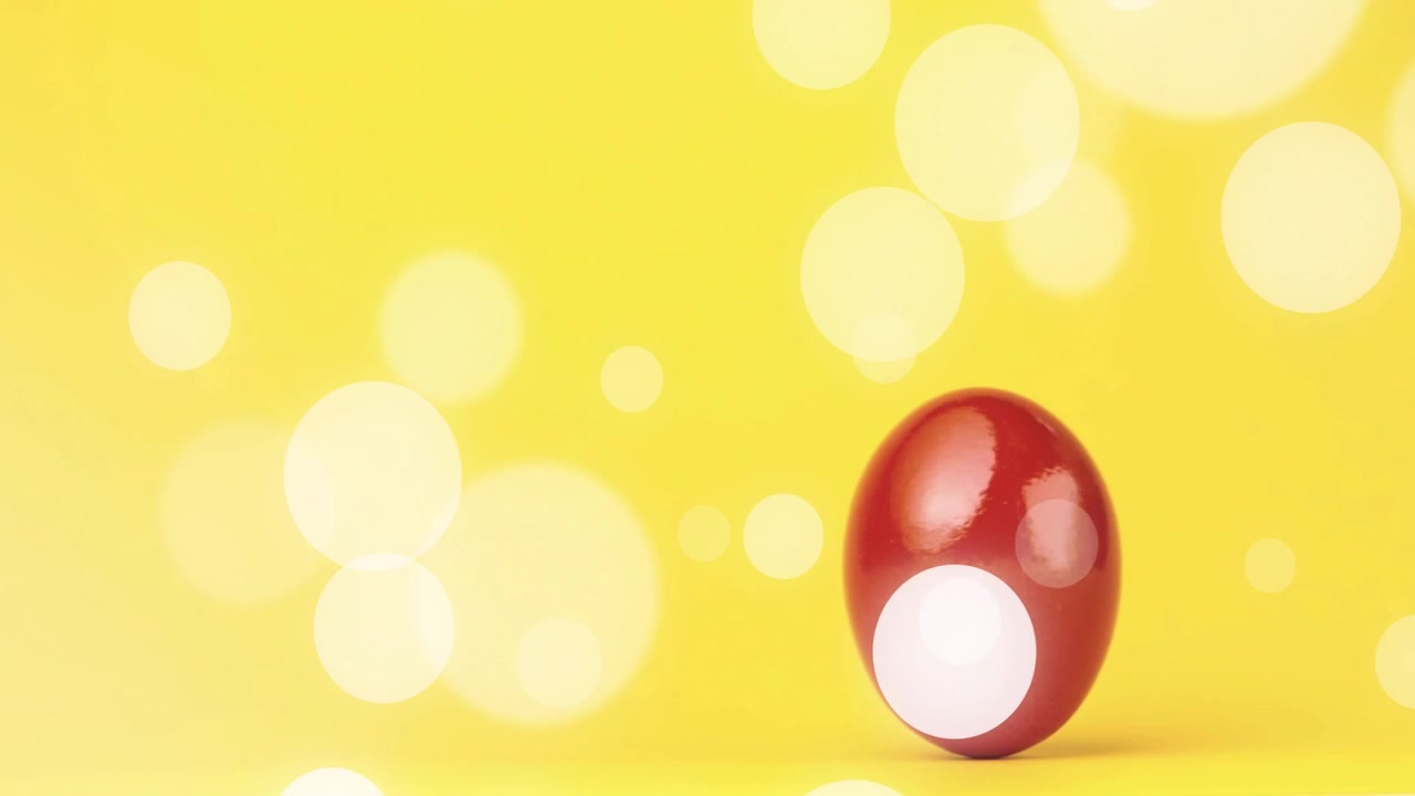 Oval merah mengkilap bergulir dari kanan ke kiri melintasi latar belakang kuning setelah sedikit dorongan, menampilkan efek bokeh