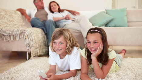 Siblings-lying-down-while-watching-the-television