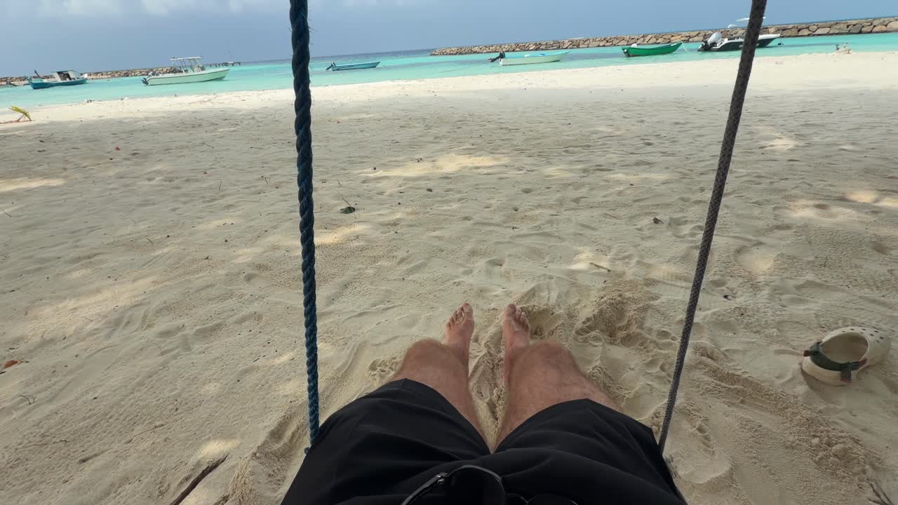 POV: Gynge på strand på Maldiverne med turkisblå lagune.