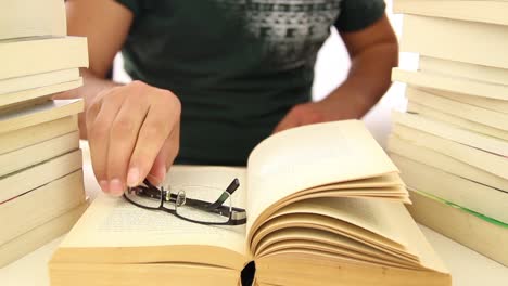 male student reading between piles of books