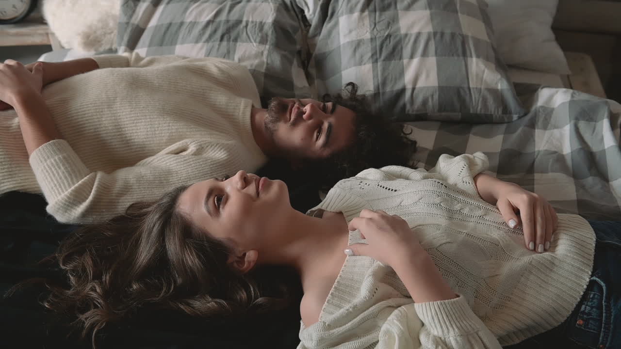 Giovane coppia romantica sdraiata a letto con vestiti invernali 1